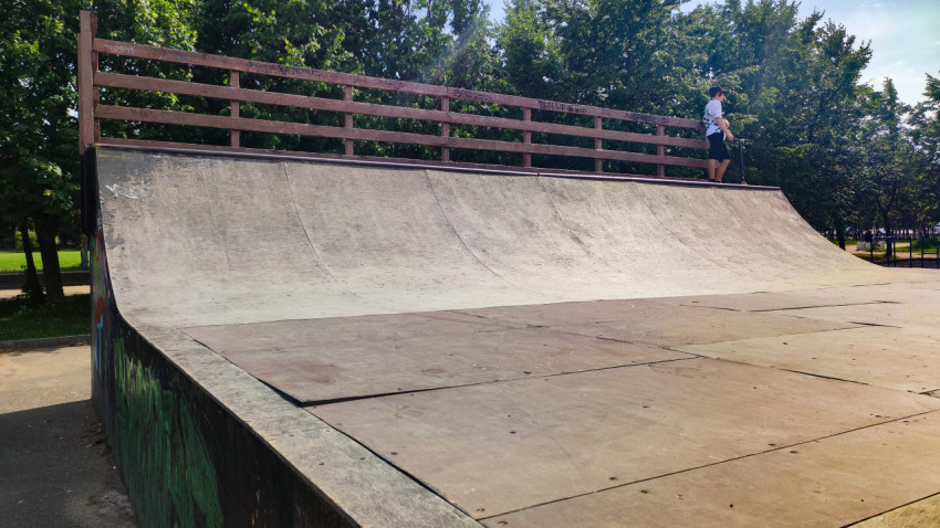 Большая рампа в скейт-парке с подростком на самокате