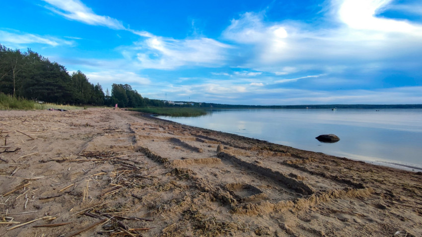 Песчаный пляж у озера с облачным небом