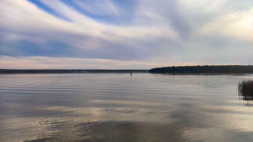 Гладкая поверхность озера с островом на горизонте