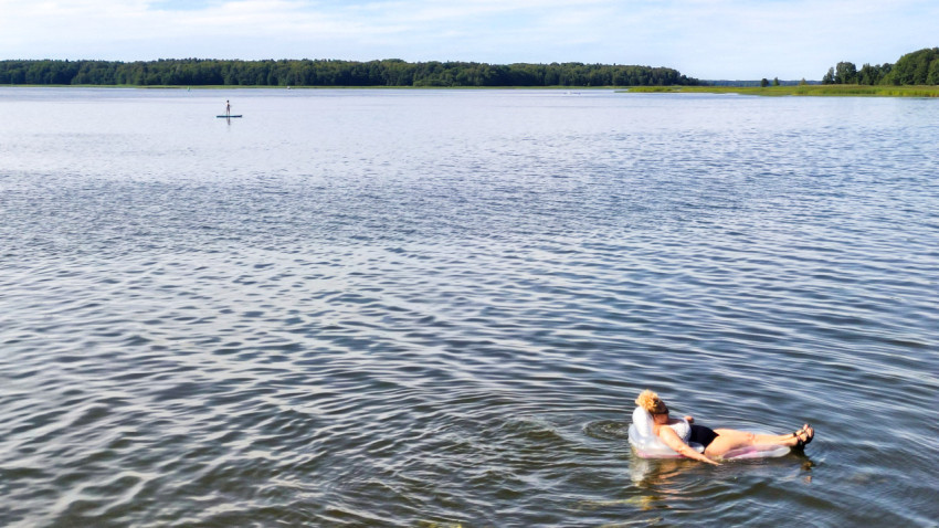 Женщина на надувном матрасе в озере