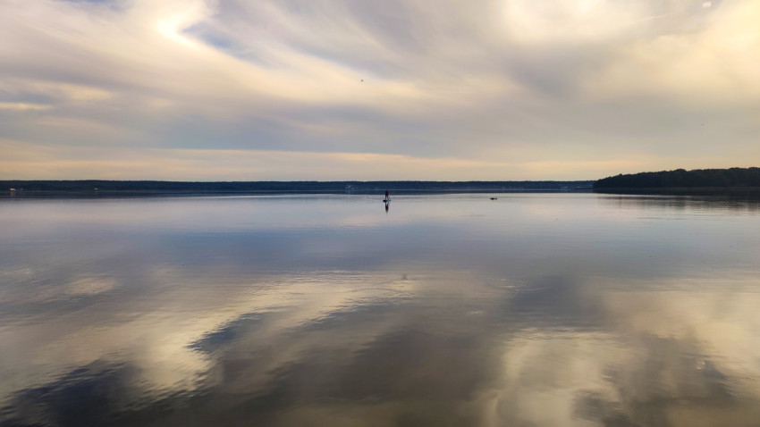 Человек на сапборде на спокойной глади озера