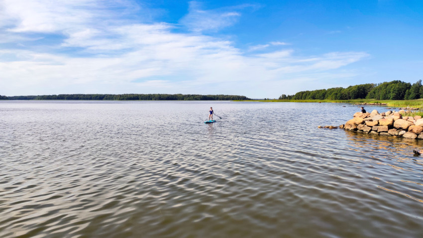 Женщина на сапборде у каменного берега