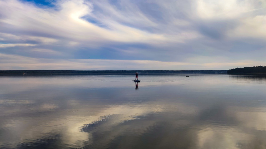 Сапбордист на озере под облачным небом
