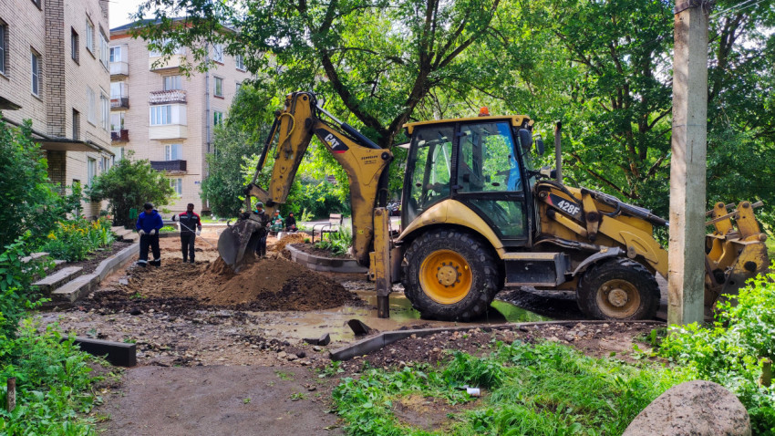 Экскаватор и рабочие на строительной площадке во дворе