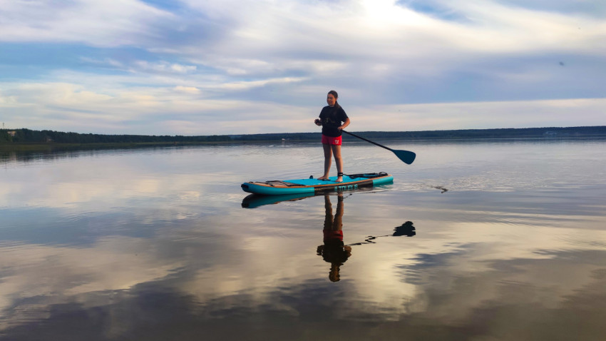 Человек на сапборде у берега озера