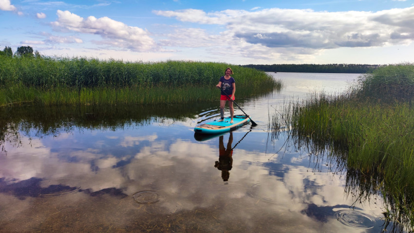 Женщина на сапборде в узком заливе озера