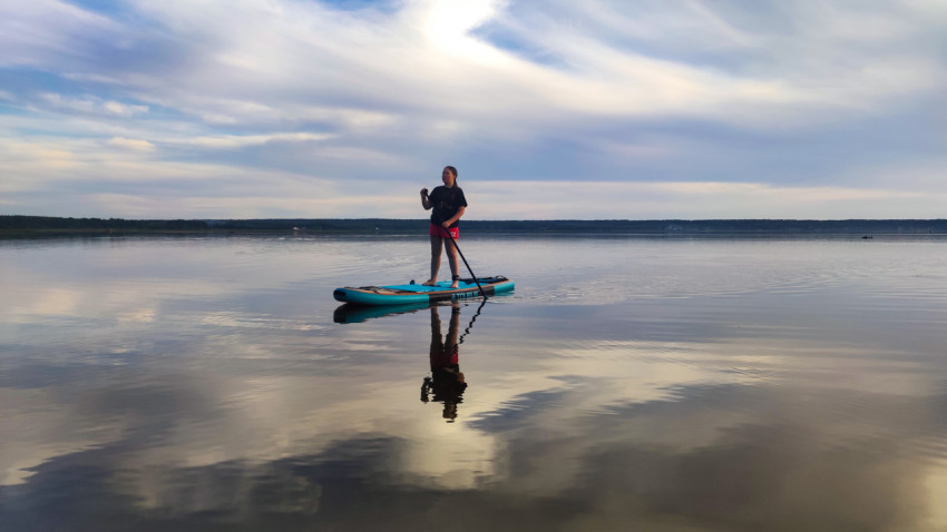 Человек на сапборде вблизи берега озера