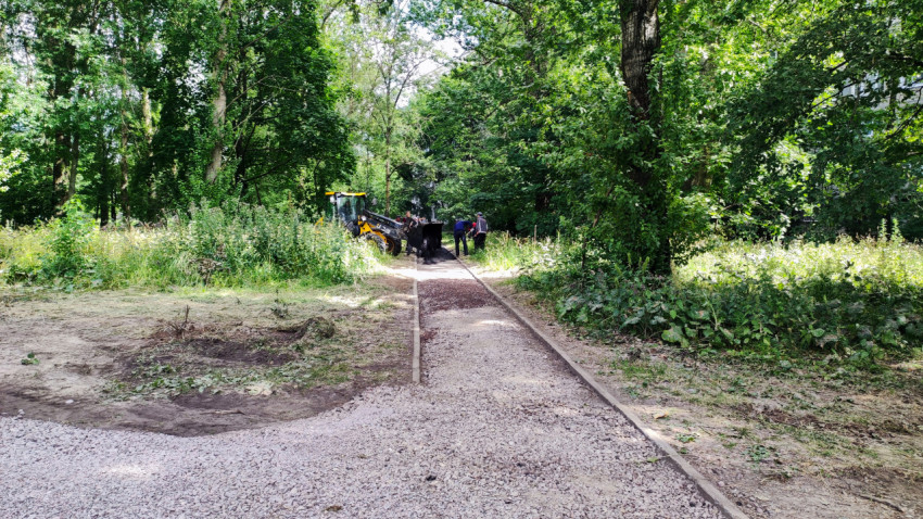 Рабочие и техника при подготовке дорожки в зелёной зоне