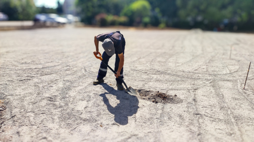 Рабочий с лопатой на строительной площадке двора