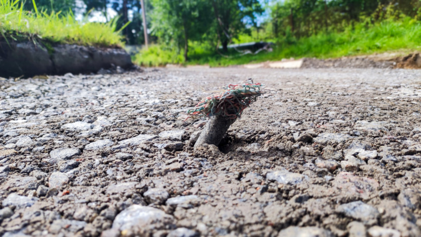 Торчащий кабель в гравийном дорожном покрытии