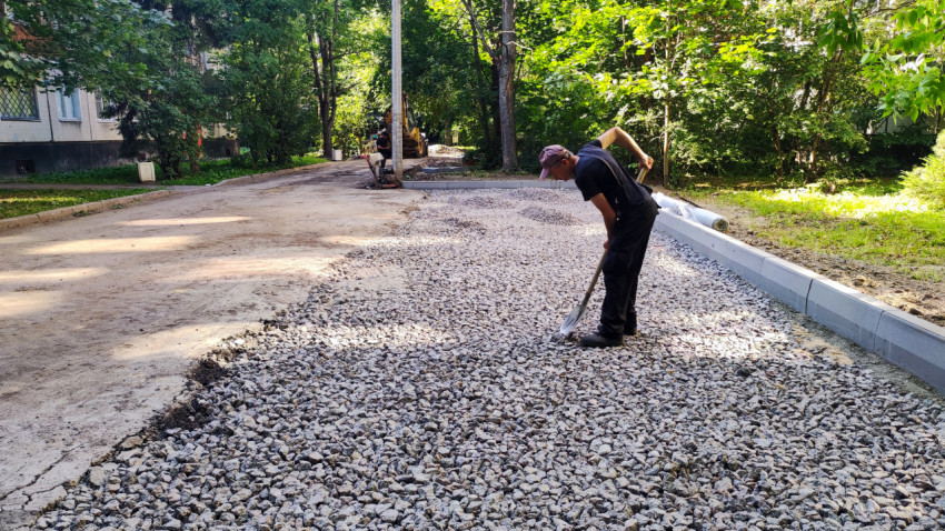 Рабочий разравнивает щебень на дорожном полотне