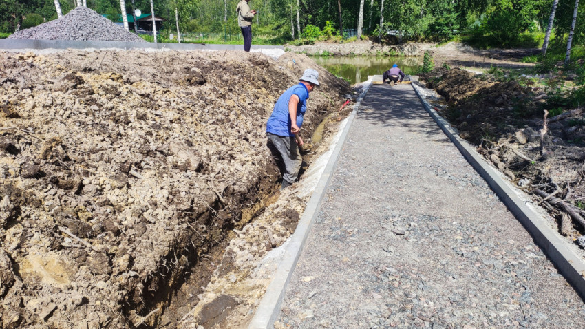 Рабочие проводят земляные работы вдоль дорожки у водоёма