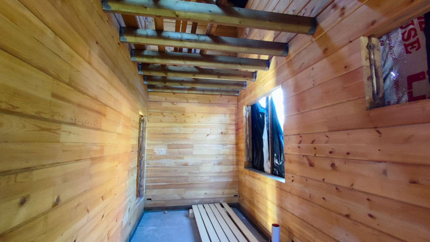 Внутреннее помещение строящегося деревянного дома с окнами и балками