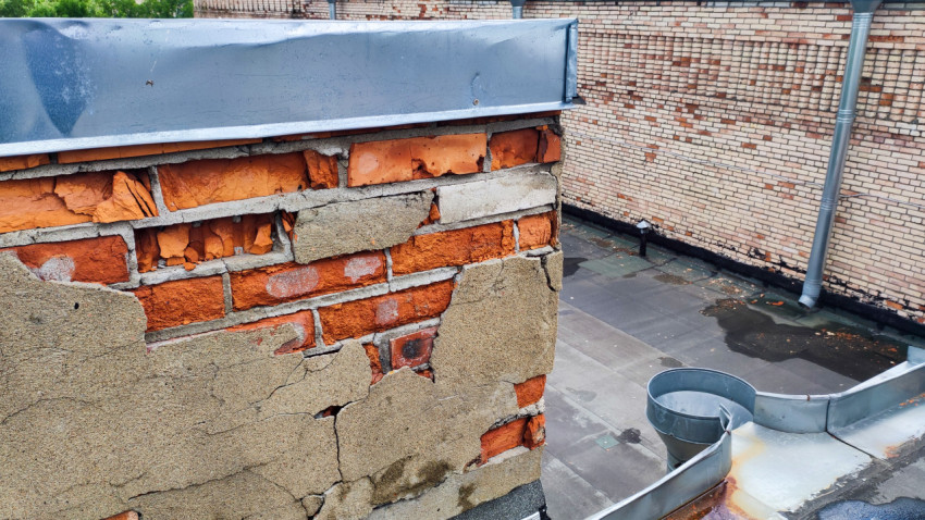 Разрушенный участок кирпичной стены на крыше дома