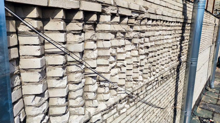 Кирпичная стена здания с сильными повреждениями кладки