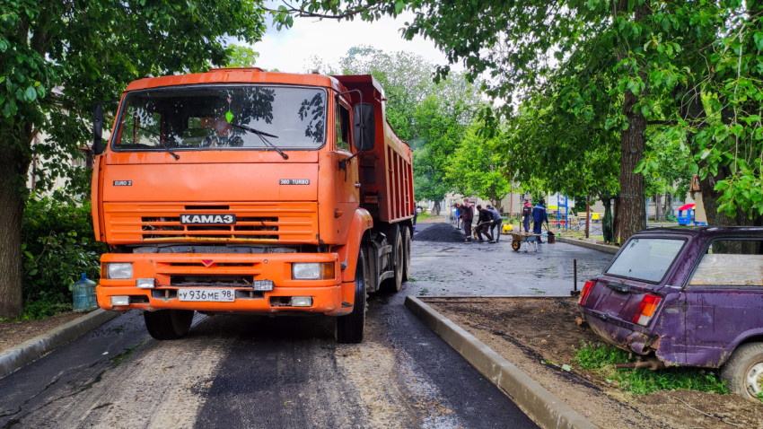 Грузовик КАМАЗ на ремонтируемой улице во дворе жилого района