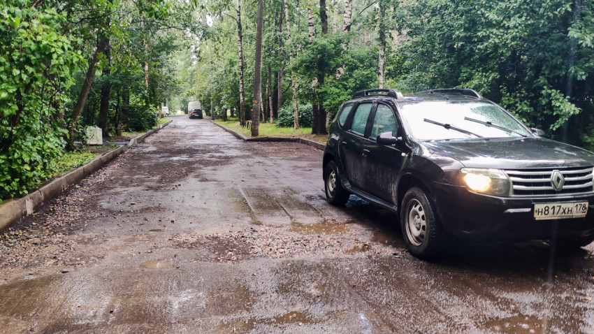 Дворовая дорога без асфальта с припаркованным автомобилем