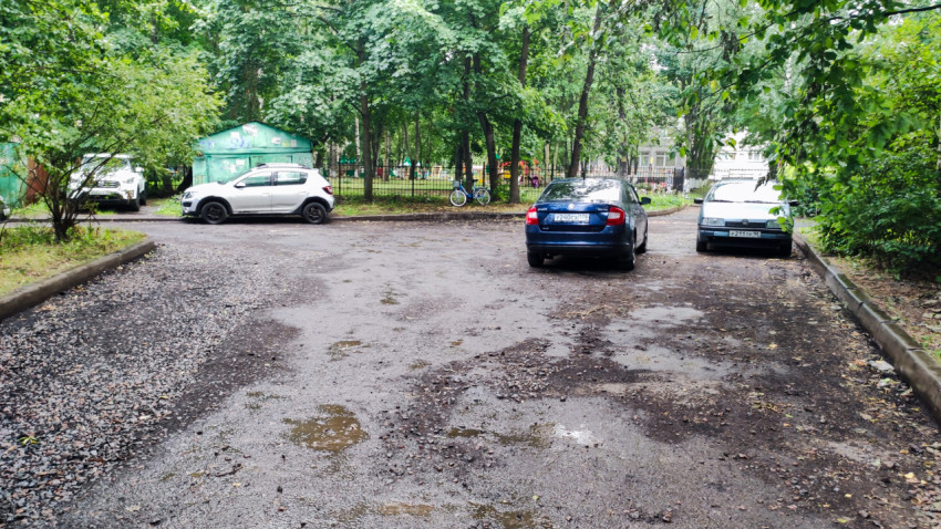 Двор с припаркованными машинами и частично отремонтированным покрытием