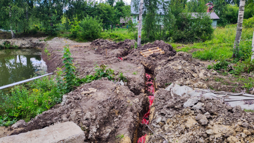 Траншея для кабельных сетей на участке у водоёма