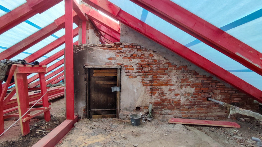 Кирпичная стена и деревянные стропила под крышей