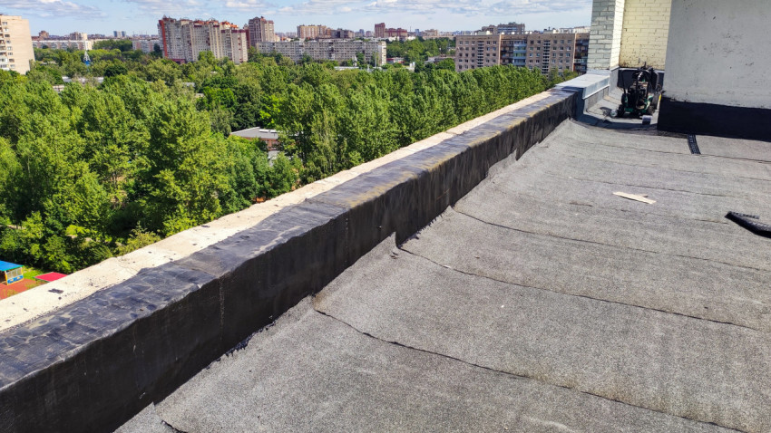 Крыша жилого дома с новым покрытием и видом на городскую застройку