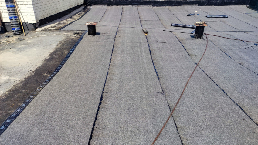 Укладка рулонного кровельного материала на крыше дома