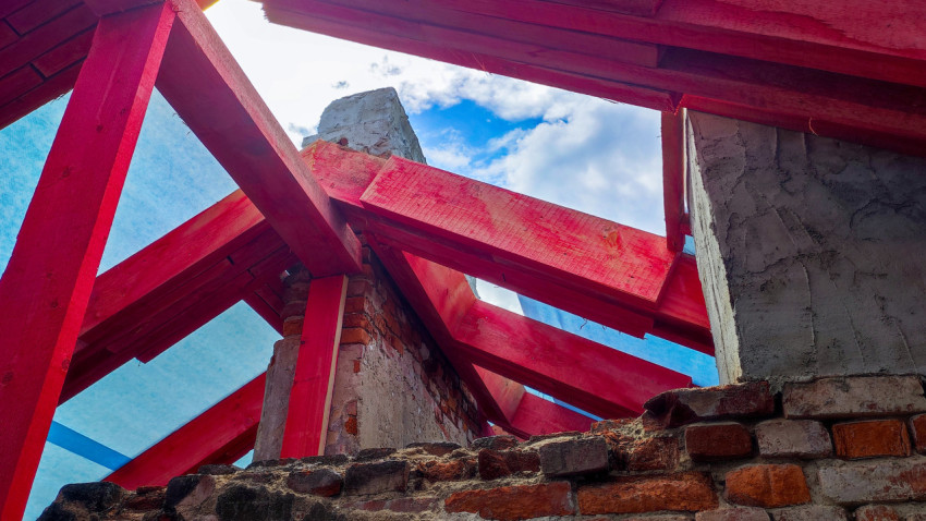Красные стропильные балки крыши с видом на кирпичную кладку