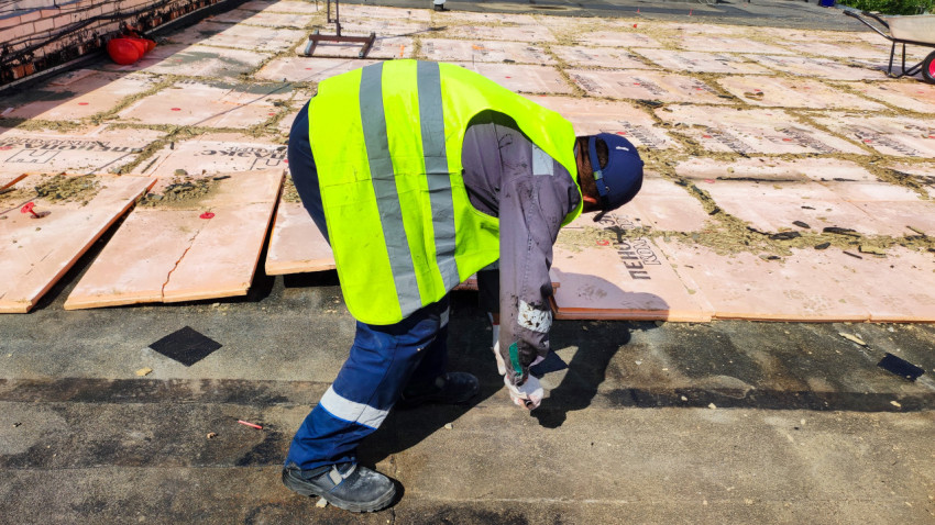 Рабочий устанавливает утеплительные плиты на крыше