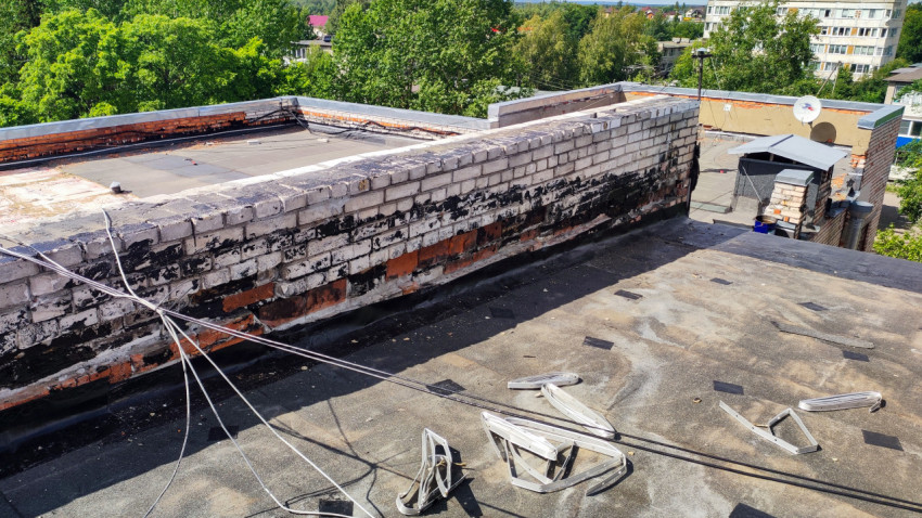 Кирпичный парапет и кабели на крыше здания