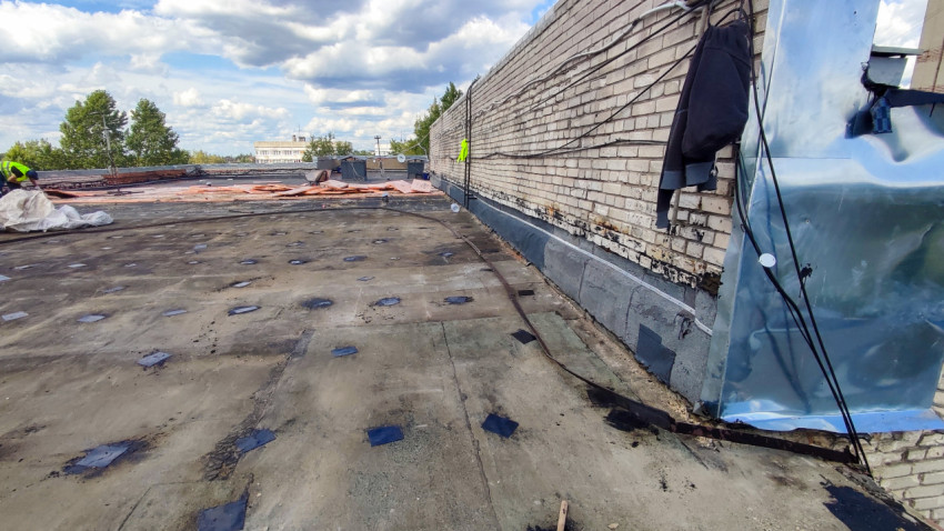 Работы на плоской крыше у кирпичной стены