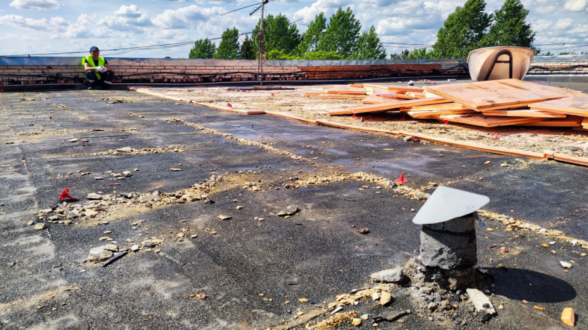 Рабочий на крыше во время демонтажа утеплителя