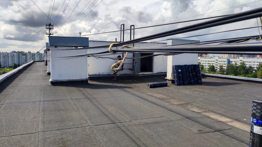 Рулоны гидроизоляции и технические сооружения на крыше жилого дома