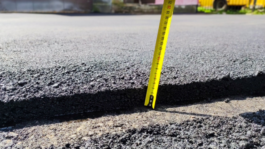 Измерение толщины слоя свежего асфальта на дороге