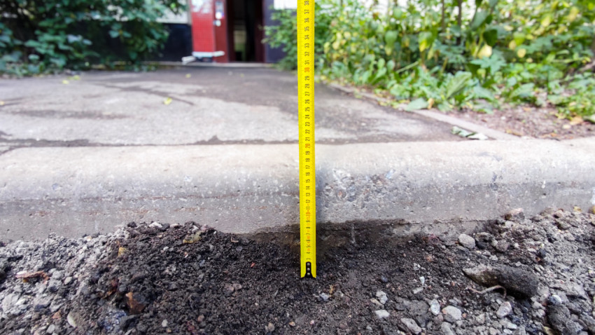 Замер высоты бордюра строительной рулеткой