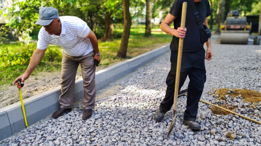Рабочие измеряют высоту бордюра при ремонте дороги