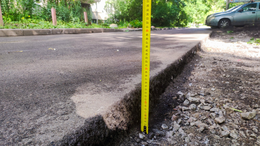 Измерение толщины нового асфальта строительной рулеткой