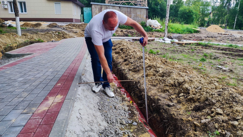 Замер глубины траншеи при строительных работах