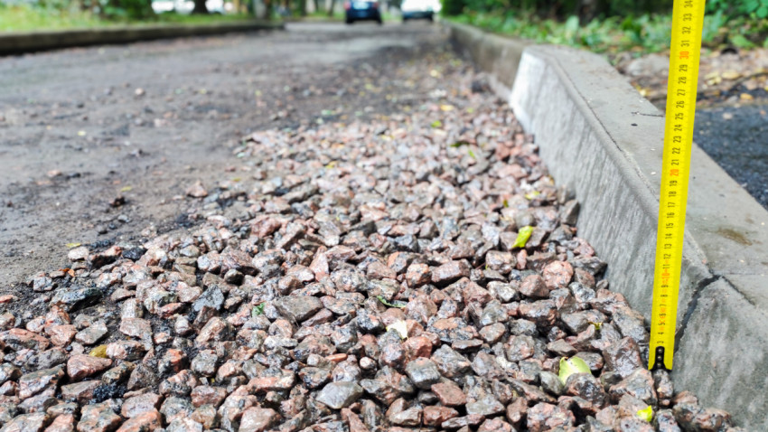 Измерение высоты бордюра рулеткой на щебёночной дороге