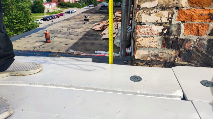 Измерение высоты утеплителя на краю крыши здания