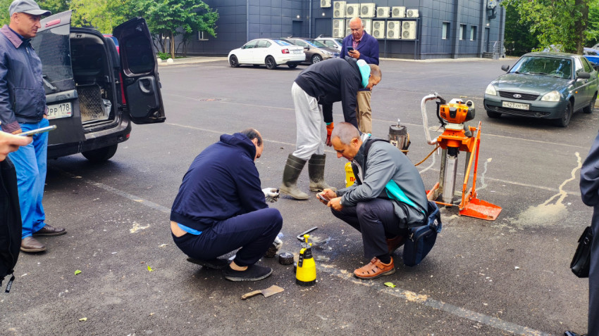 Специалисты проводят проверку асфальта на парковке у здания