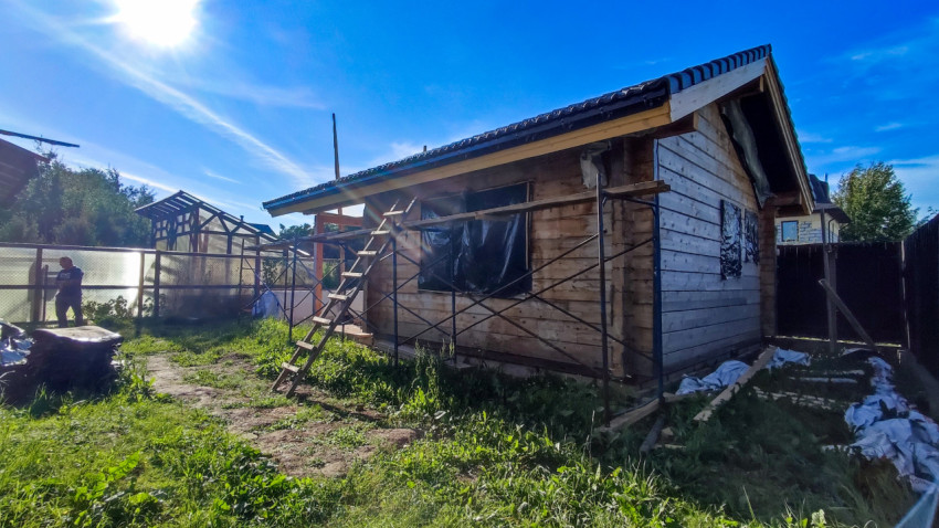 Одноэтажный деревянный дом с лестницей и строительными лесами