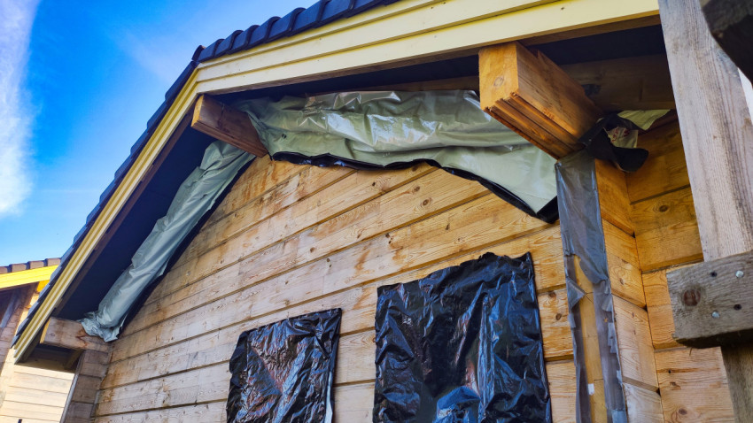 Деревянный фасад дома на этапе монтажа кровли и защитных материалов