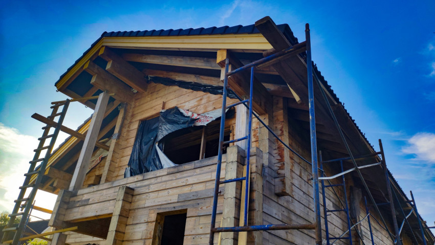 Фасад деревянного дома в процессе строительства с лесами