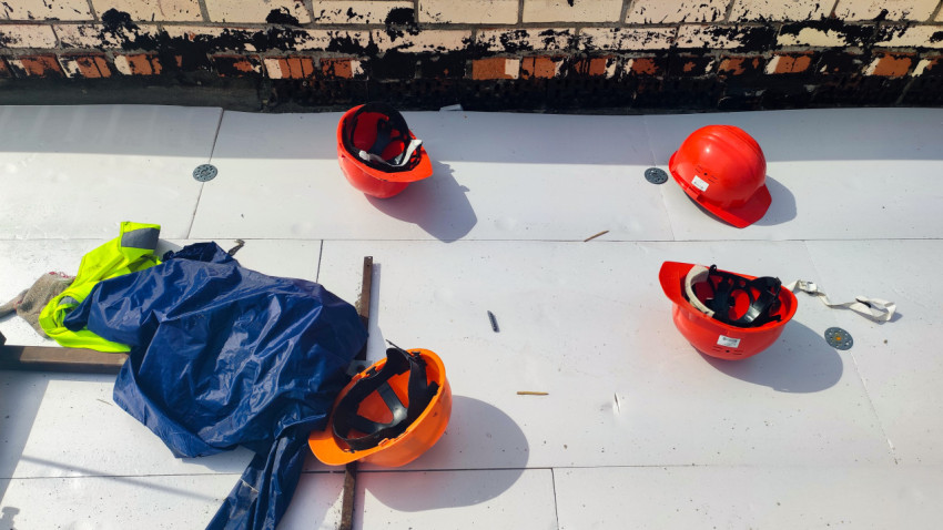 Красные каски и рабочая одежда на кровле здания