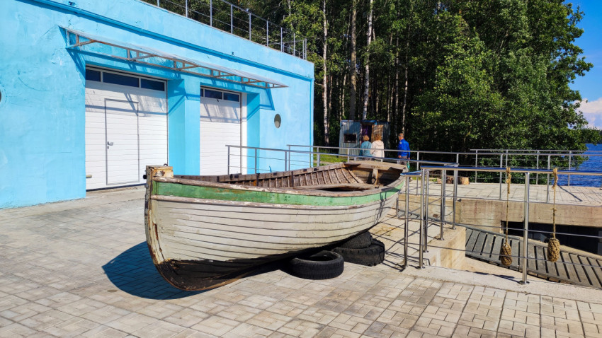 Старая деревянная лодка у здания на берегу озера
