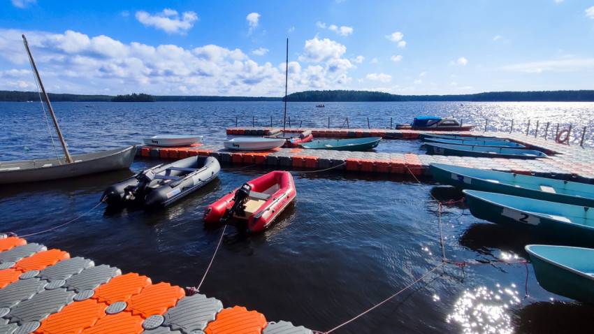 Лодки у понтона на озере с лесистым горизонтом