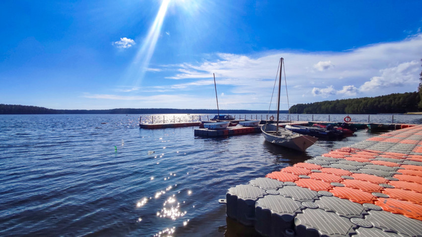 Лодки у понтона на фоне солнечного озера