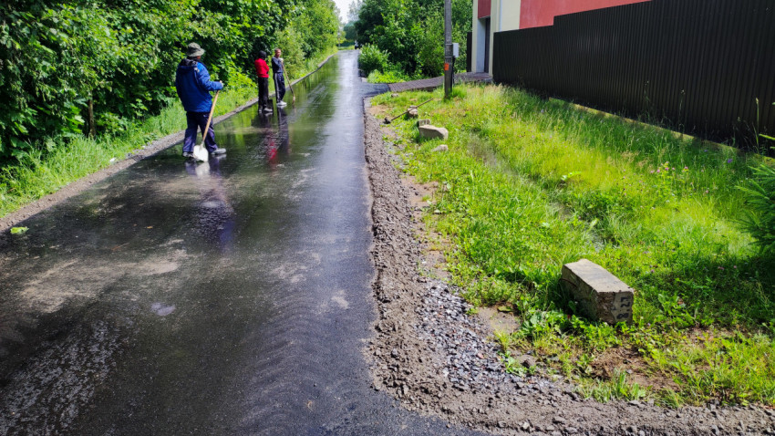 Рабочие выполняют благоустройство асфальтовой дороги после дождя