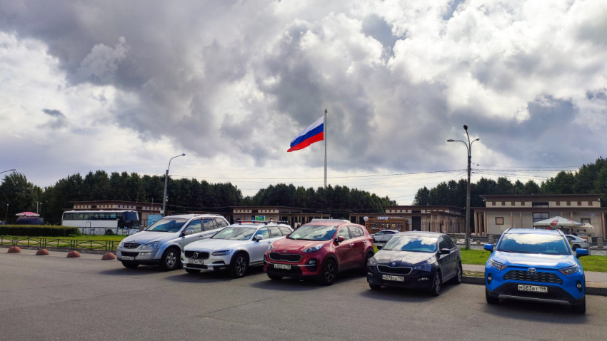 Автомобили на стоянке и российский флаг на высоком флагштоке