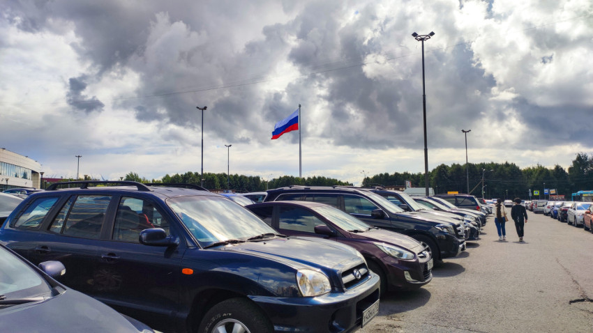 Ряды машин и государственный флаг России на парковке